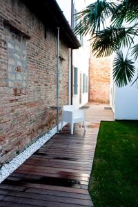 a white bench sitting on a wooden walkway next to a brick building at Legrenzi Rooms in Mestre