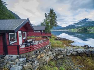 a red house with a stone wall next to a lake at Fagervik Camping in Tresfjord