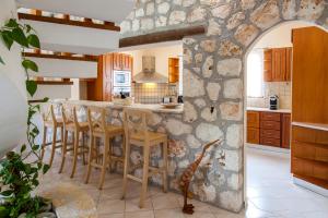 a kitchen with a stone wall and a table with stools at Villa Aliki in Vasiliki