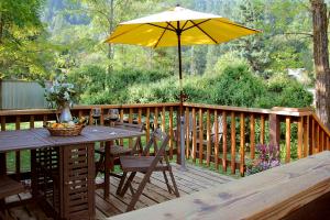 eine Holzterrasse mit einem Tisch und einem Sonnenschirm in der Unterkunft Coho Cottages in Willow Creek