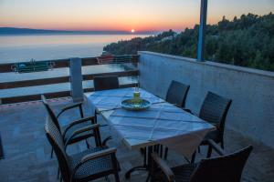 a table and chairs on a balcony with the sunset at Leonarda in Omiš