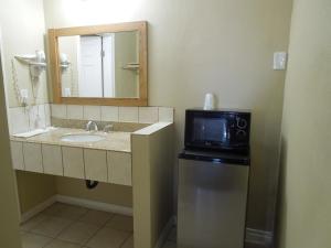 a bathroom with a sink and a mirror and a microwave at Castaway Motel in Orange +25 photos