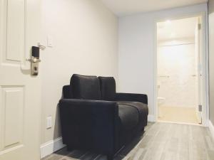 a black reclining chair in a room with a bathroom at Mayfair Inn and Suites in Queens