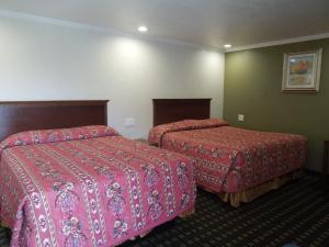 a hotel room with two beds with red sheets at Castaway Motel in Orange