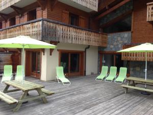 una terraza con sillas, mesas y sombrillas en Aiglon Morzine en Morzine