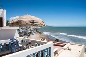 einen Balkon mit Tisch, Sonnenschirm und Strand in der Unterkunft Laverie du Soleil Surf House in Taghazout