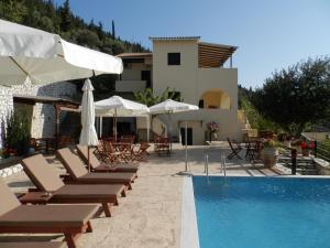 a group of chairs and umbrellas next to a pool at Green Villa in Agios Nikitas