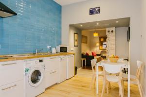 uma cozinha com uma máquina de lavar roupa e uma mesa com cadeiras em La Accesoria Del Arenal em Sevilha