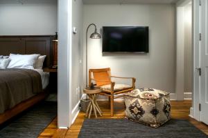 a bedroom with a bed and a chair and a tv at Western Front Hotel in Saint Paul