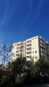 un grand immeuble d'appartements avec des arbres devant lui dans l'établissement Geni Apartment, à Durrës