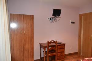 Habitación con escritorio con silla y TV en la pared. en Hostal Arévacos en Soria