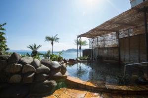 a swimming pool in front of a house with the ocean at Ibusuki Royal Hotel in Ibusuki