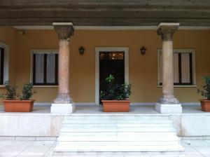 a building with columns and potted plants in front of it at Romeo Design Rooms in Verona