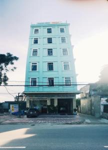 un edificio alto azul con un coche aparcado delante de él en Thanh Binh Hotel en Ha Tinh