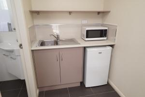 eine kleine Küche mit einer Spüle und einer Mikrowelle in der Unterkunft Exies Bagtown in Griffith
