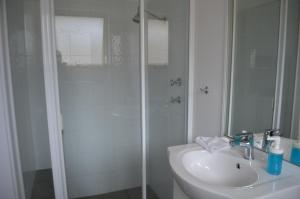 a bathroom with a shower, sink, and mirror at Harbourside Motel in Albany