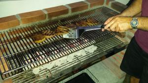 a person holding a spatula cooking food on a grill at Cleopatra Villas - Sea View in Rodney Bay Village