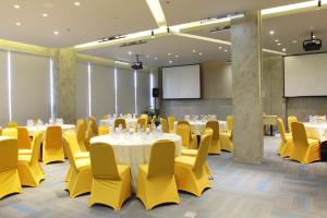 uma sala de conferências com mesas e cadeiras amarelas em Yello Hotel Jemursari em Surabaia