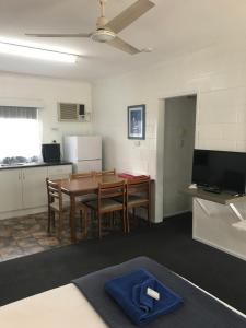 a kitchen with a table and a refrigerator at Tramway Motel in Sarina