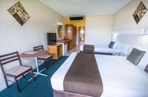 um quarto de hotel com uma cama grande e uma mesa e cadeiras em Elkira Court Motel em Alice Springs