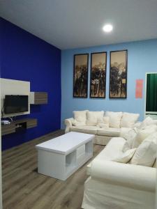 a living room with white couches and a tv at Xenia Homestay in Kuching