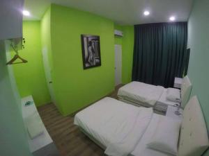 um quarto com duas camas e uma parede verde em Xenia Homestay em Kuching