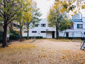 a playground in front of a white building with trees at 2no HOME & PARK in Kobe