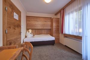 - une petite chambre avec un lit et une fenêtre dans l'établissement Pension Gabi, à Saalbach-Hinterglemm