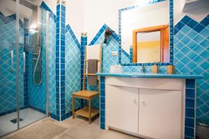 bagno piastrellato blu con lavandino e doccia di Le Stanze Del Centro a San Teodoro