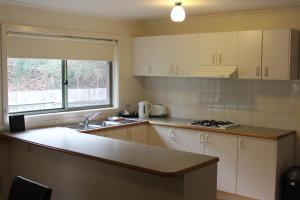 een keuken met witte kasten en een aanrecht bij Australian Home Away Ringwood Bardia in Ringwood
