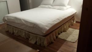 un letto con lenzuola bianche e cuscini sopra di Alona a Kefar Weradim