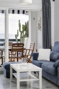 Una sala de estar con un sofá azul y una mesa. en Marina Playa, en La Herradura