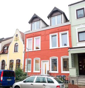 un edificio rojo con un coche aparcado delante de él en FeWo Engler Bremen Ritterhuder Straße, en Bremen