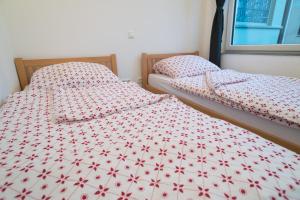 2 letti singoli in una camera da letto con trapunta rossa e bianca. di FeWo Engler Bremen Ritterhuder Straße a Brema