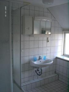 ヴェスターラントにあるGrenzhof-Kapitaenswohnungの白いタイル張りのバスルーム(シンク、鏡付)