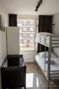 Katwijk aan ZeeにあるAppartement Zee en Duinzicht 78のベッドルーム1室(二段ベッド2台、窓付)が備わります。