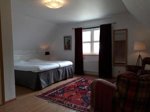 Schlafzimmer mit einem Bett, einem Fenster und einem Teppich in der Unterkunft Linda Gård in Yngsjö