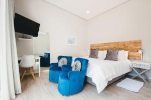a bedroom with a bed and two blue chairs at A Riverbed Guesthouse in Swellendam