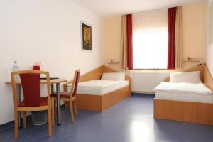 a room with two beds and a table and chair at Sporthotel Borussia Düsseldorf in Düsseldorf +28 photos