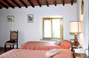 1 dormitorio con 2 camas, silla y ventana en Casa Corella, en Ampinana