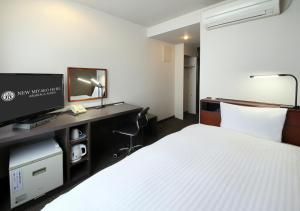 ein Hotelzimmer mit einem Bett und einem Schreibtisch mit einem Fernseher in der Unterkunft New Miyako Hotel Ashikaga Annex in Ashikaga