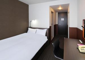 ein kleines Zimmer mit einem Bett und einem Schreibtisch in der Unterkunft New Miyako Hotel Ashikaga Annex in Ashikaga + 11 Fotos