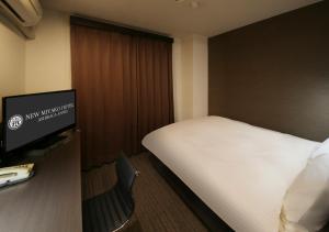a hotel room with a bed and a flat screen tv at New Miyako Hotel Ashikaga Annex in Ashikaga