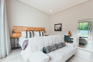 A Riverbed Guesthouse في سويلندام: غرفة نوم بيضاء مع سرير كبير وأريكة