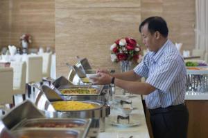 波來古的住宿－慶靈酒店，餐馆厨房里准备食物的人