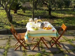 a picnic table with fruit on it with two chairs at Baglio Delle Rose in Giarre