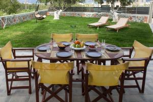 a wooden table with chairs and a bowl of fruit on it at Evangelie Residence a brand new design apartment 5 minutes from the sea with a large garden in Kissamos