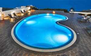 a large blue swimming pool on a patio at night at Golden East in Imerovigli