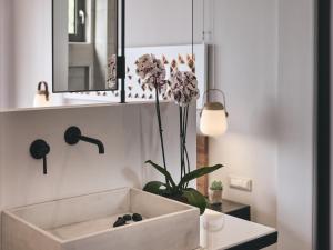 a bathroom with a sink and a vase with flowers at Hotel St.John Suites Adults Only in Tsilivi