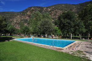 a swimming pool with people in it with mountains in the background at Camping Noguera Pallaresa in Sort